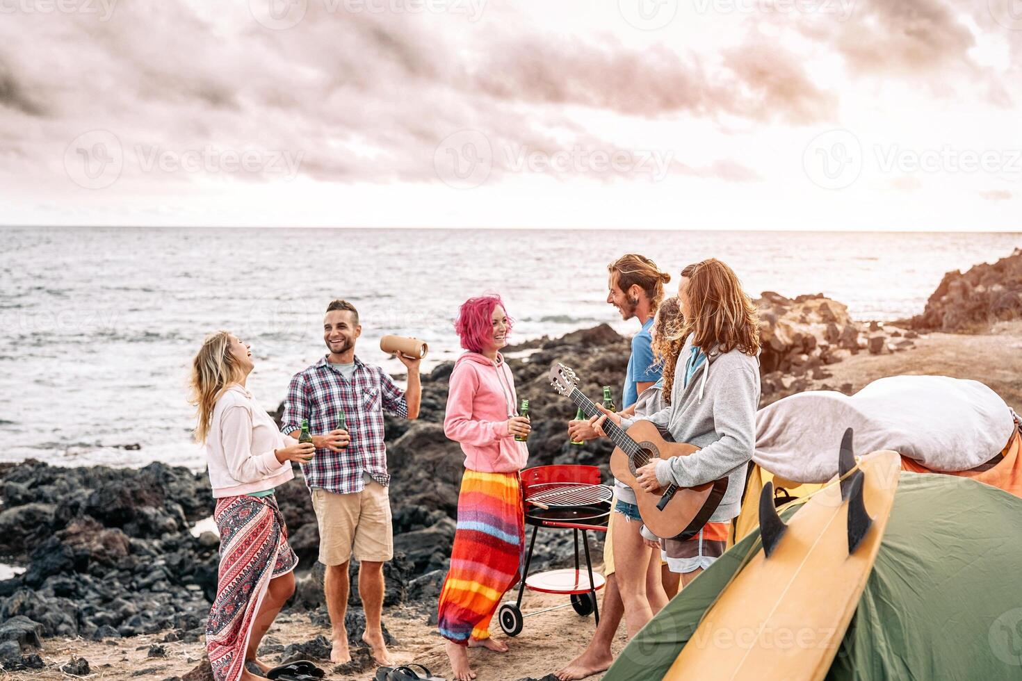 feliz surfista amigos fazer festa às pôr do sol enquanto acampamento Próximo a de praia - jovem pessoas tendo Diversão e bebendo Cerveja ao ar livre - milenar, verão, período de férias e juventude feriados estilo de vida conceito foto