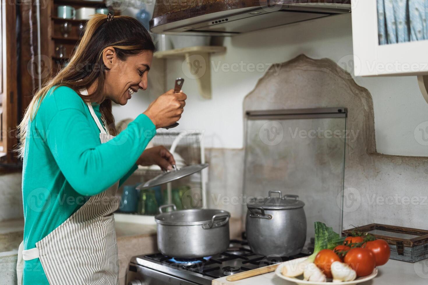 latim maduro mulher cozinhando dentro velho vintage cozinha - sorridente mãe preparando almoço às casa foto