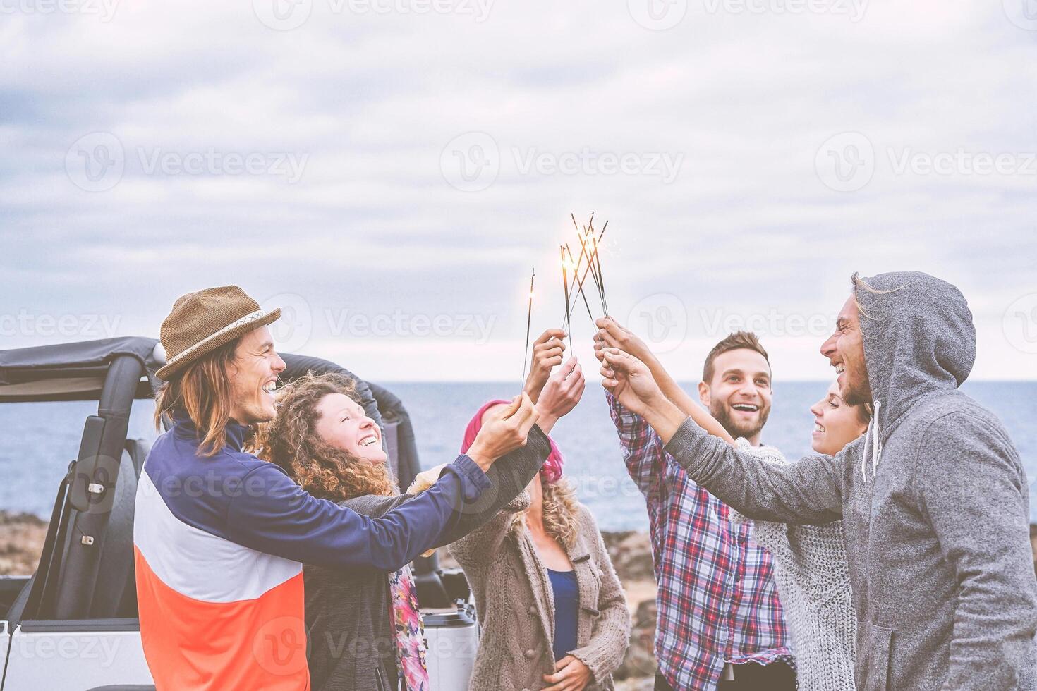 feliz grupo do amigos a comemorar com espumante estrelas fogos de artifício Próximo para oceano - viagem pessoas tendo Diversão desfrutando uma momento dentro uma estrada viagem - conceito do amizade, juventude estilo de vida e festa foto