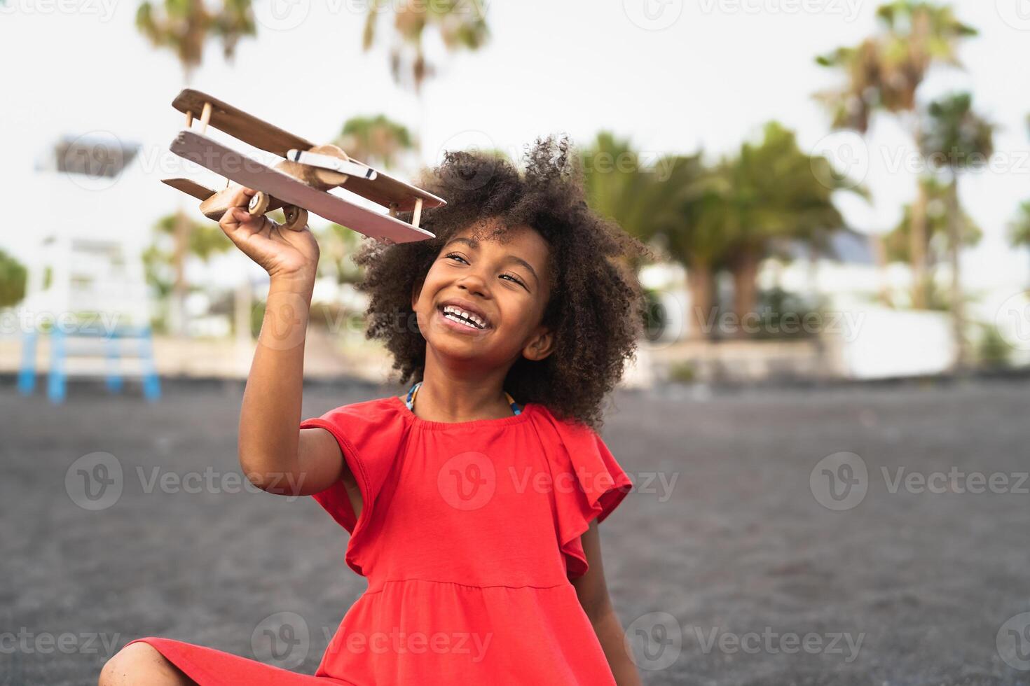 afro criança jogando com madeira brinquedo avião em a de praia - pequeno criança tendo Diversão durante verão feriados - infância e viagem período de férias conceito foto