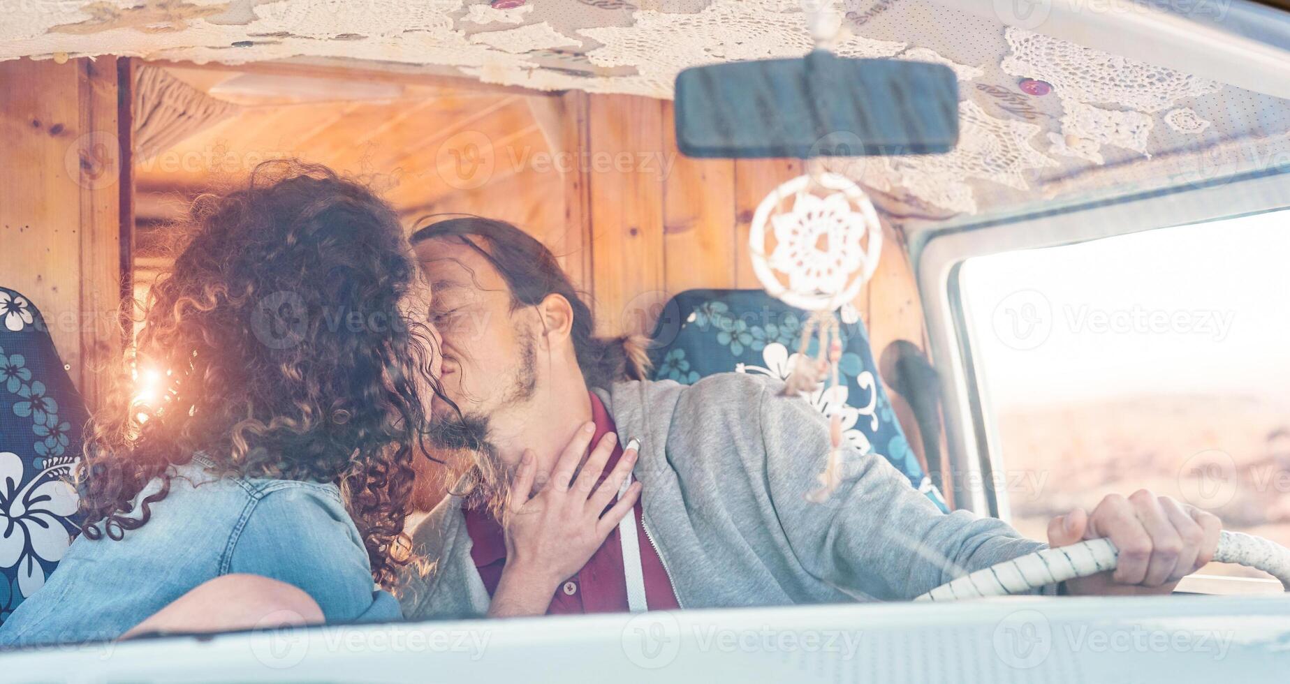 feliz casal se beijando dentro uma vintage mini furgão - romântico amantes tendo uma concurso momento durante uma viagem - pessoas relação, férias, viagem e transporte conceito foto