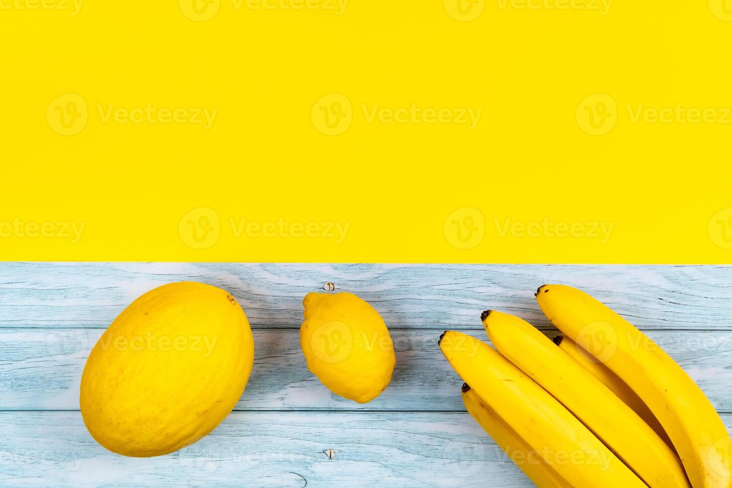 a sortimento do amarelo frutas mentiras em uma azul de madeira fundo e uma amarelo fundo foto