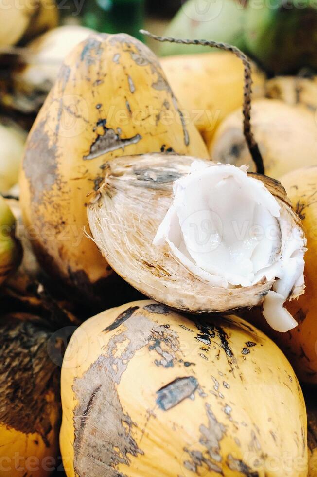 amarelo cocos estão vendido dentro a mercado do a ilha do maurício. cortar uma jovem coco com makoto. muitos cocos em a mercado foto