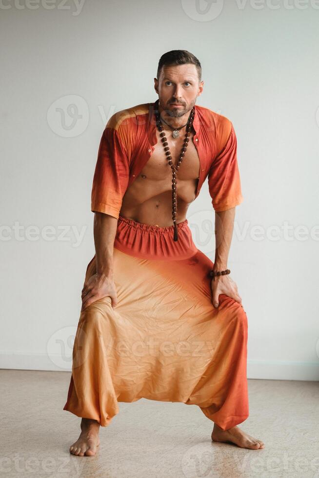 uma homem dentro a laranja terno faz ioga de comovente dele abdominal músculos dentro a academia. a conceito do saúde foto