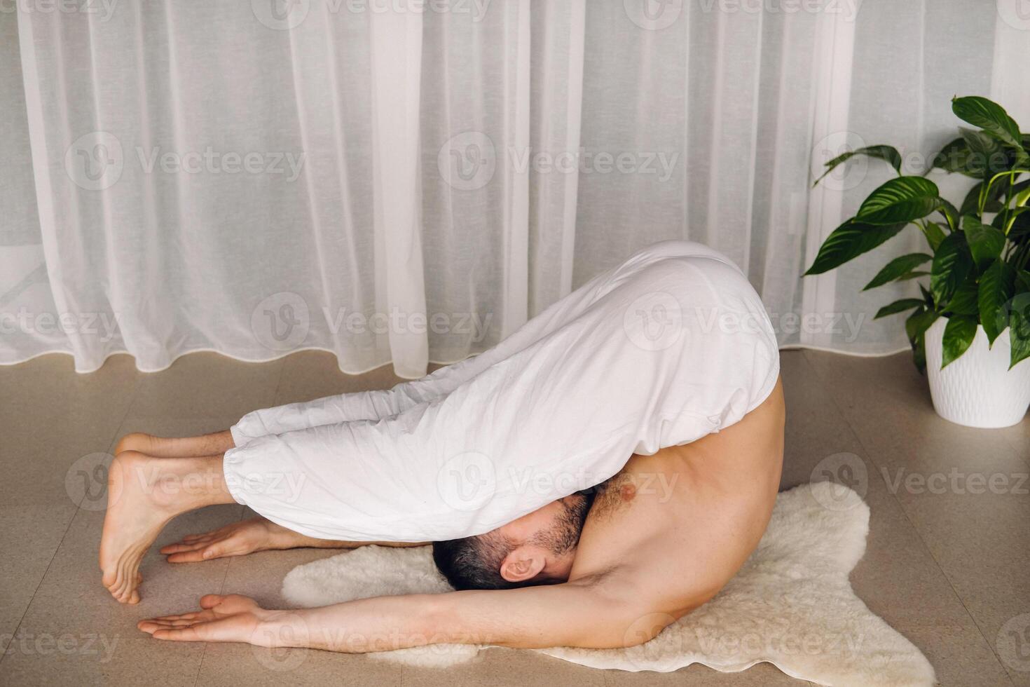 uma homem com uma nu tronco faz ioga dentro uma ginástica sala. a conceito do uma saudável estilo de vida foto