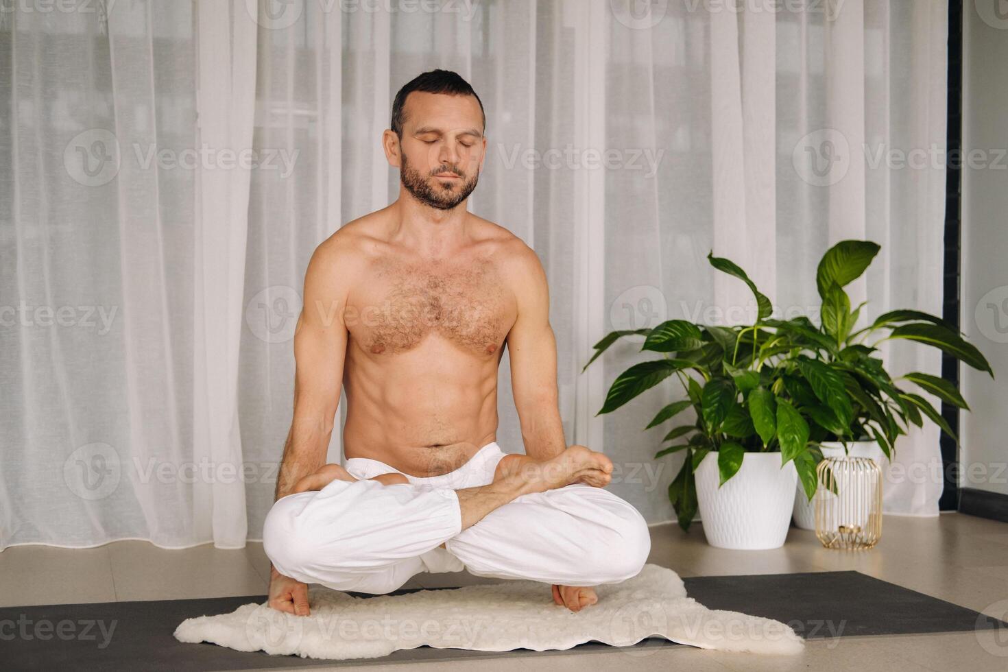 uma homem com uma nu tronco faz ioga dentro uma ginástica sala. a conceito do uma saudável estilo de vida foto