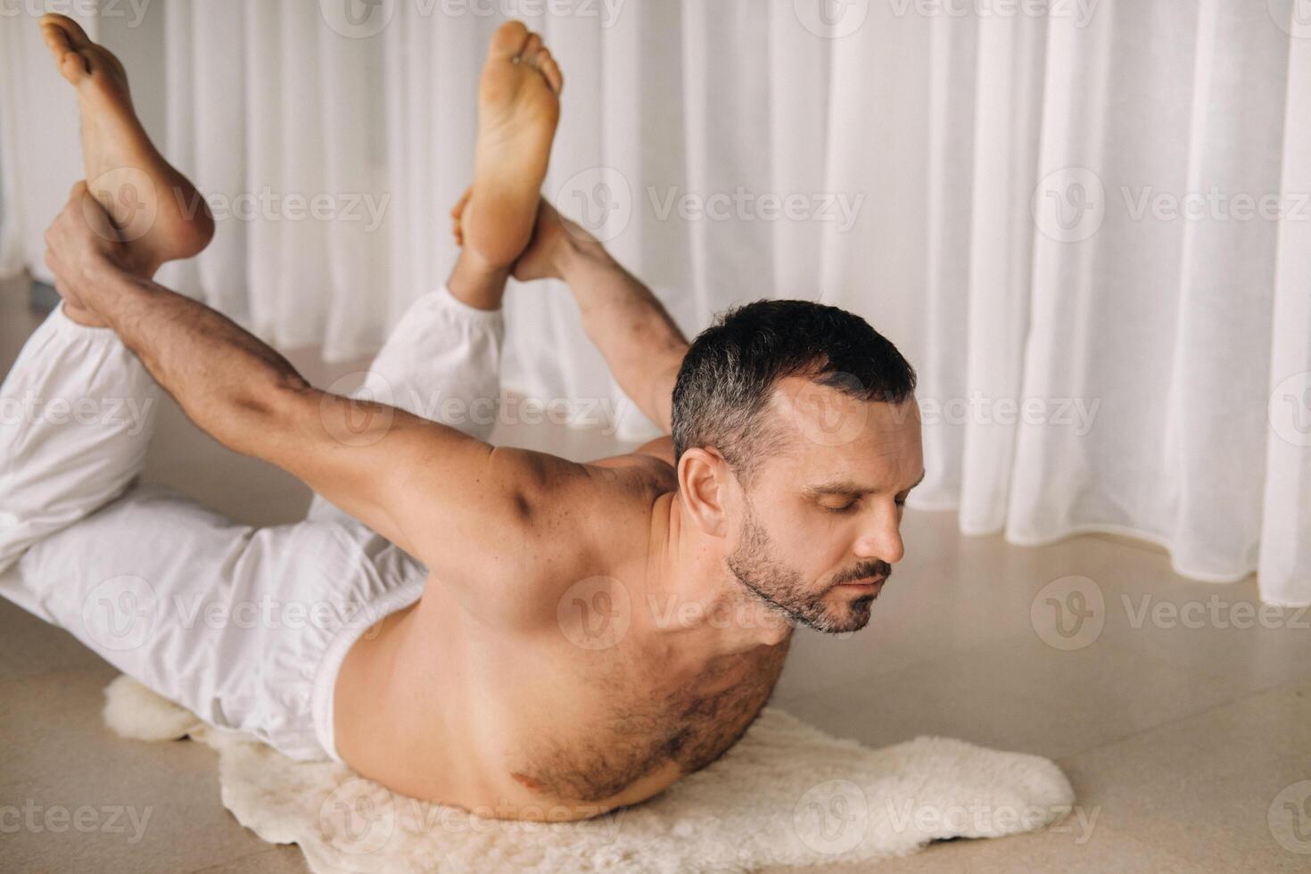 uma homem com uma nu tronco faz ioga dentro uma ginástica sala. a conceito do uma saudável estilo de vida foto