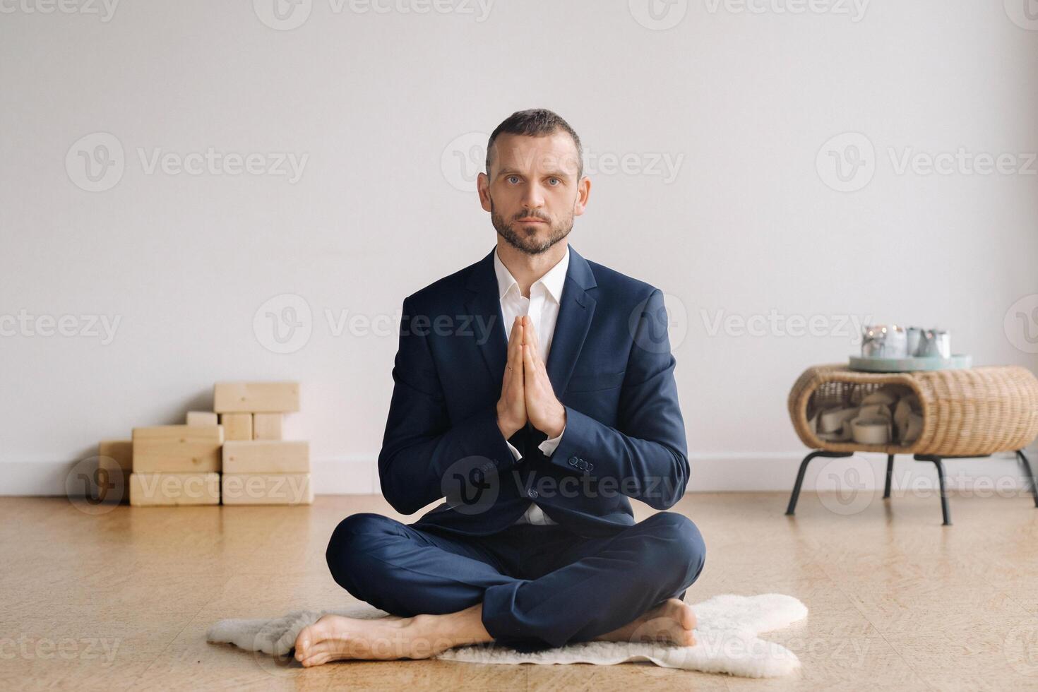 uma homem dentro uma rigoroso terno faz ioga enquanto sentado dentro uma ginástica quarto foto