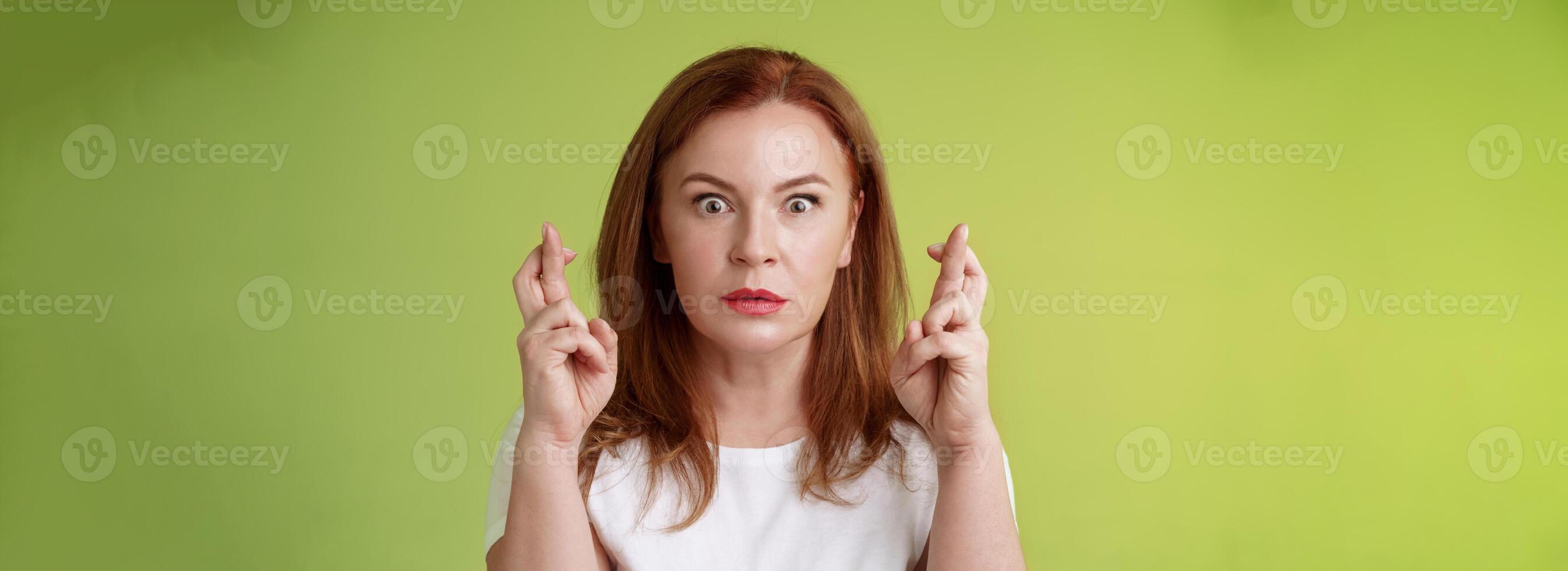 atordoado intenso preocupado meia idade ruiva mulher olhar fixamente nervosamente aguardando importante resultado implorar Sonhe venha verdade receber positivo resposta em pé estupor verde fundo faço desejo Boa sorte foto