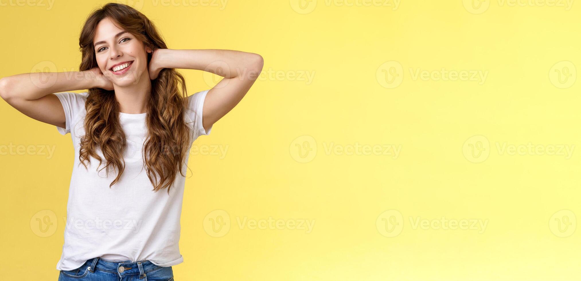 despreocupado casual urbano menina tendo verão feriado apreciar ensolarado perfeito caloroso dias vestem branco camiseta jeans aguarde mãos pescoço preguiçoso esticam sorridente amplamente relaxante em repouso período de férias ficar de pé amarelo fundo foto