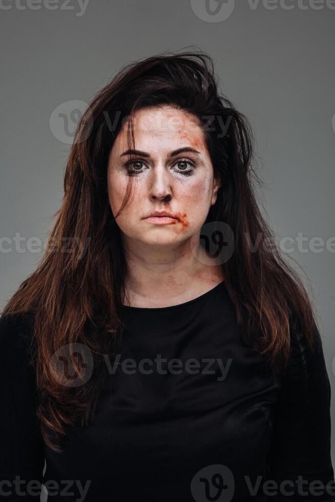 uma maltratado mulher dentro Preto roupas em a isolado cinzento fundo. violência contra mulheres foto