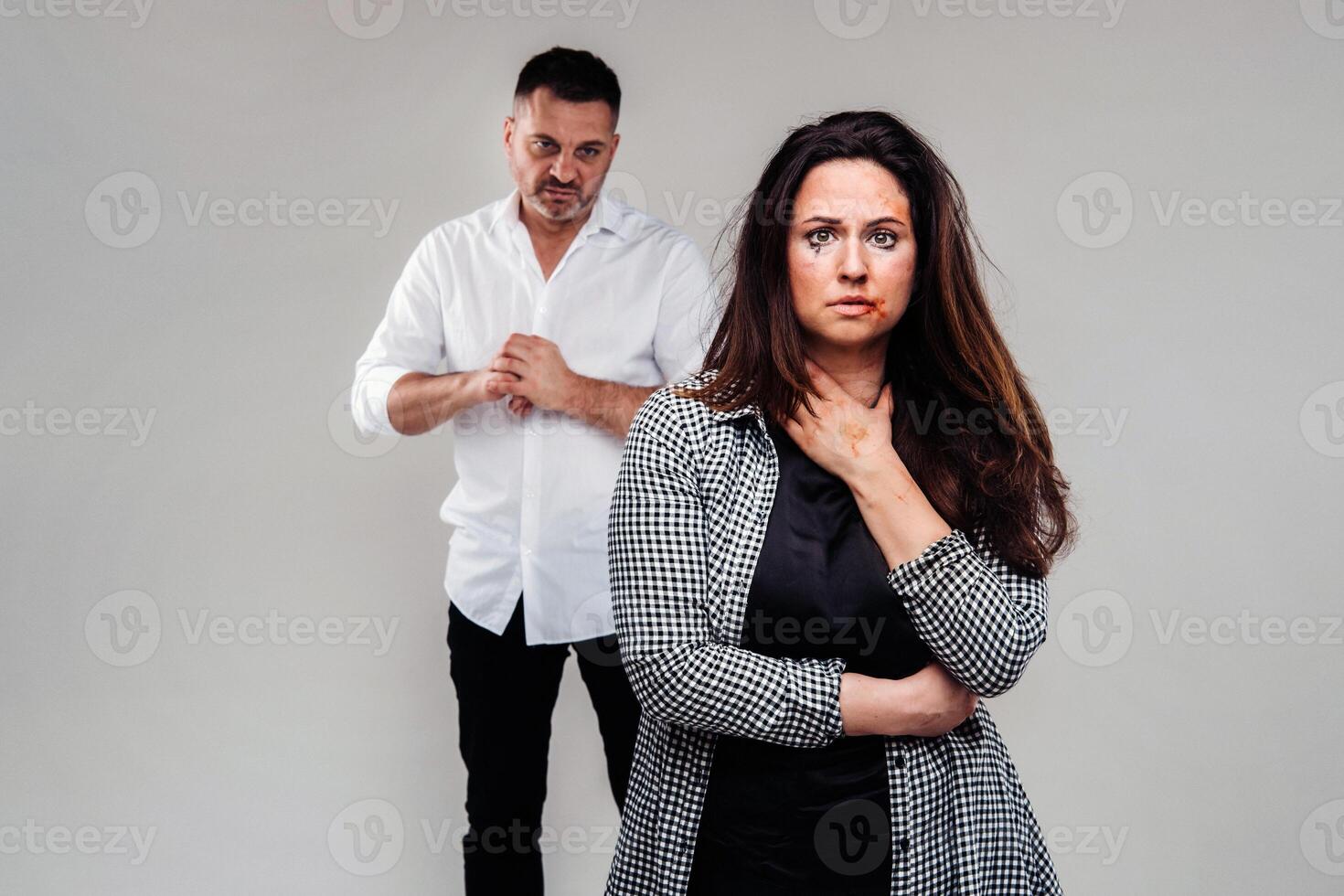 uma mulher espancado de dela marido em pé atrás dela e olhando às dela agressivamente. doméstico violência foto
