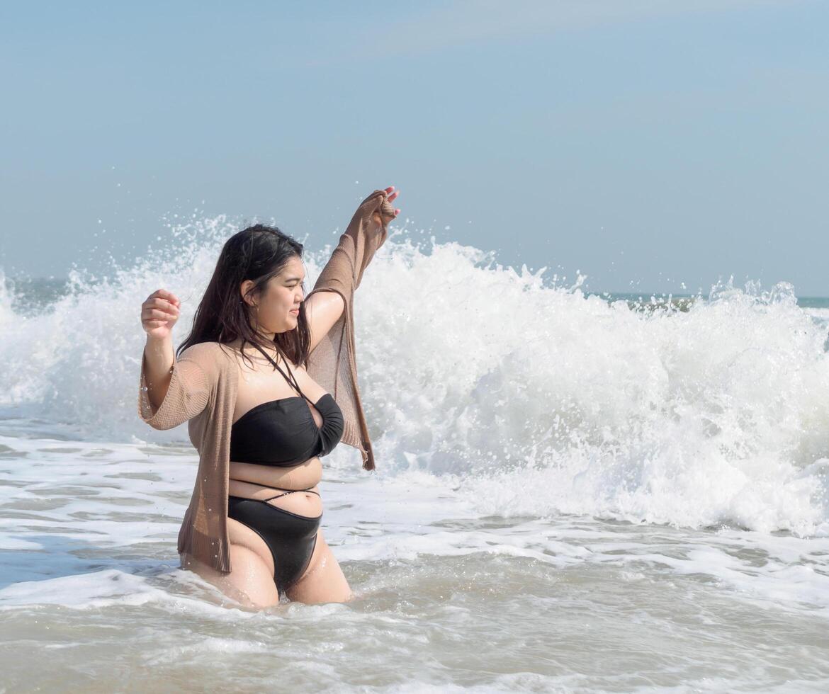 retrato jovem ásia mulher gordo gordo fofa lindo sorrir feliz Diversão apreciar relaxar bikini roupa de banho corpo sexy frente Visão mar de praia branco areia limpar \ limpo céu azul calma natureza oceano onda água viagem em feriado foto