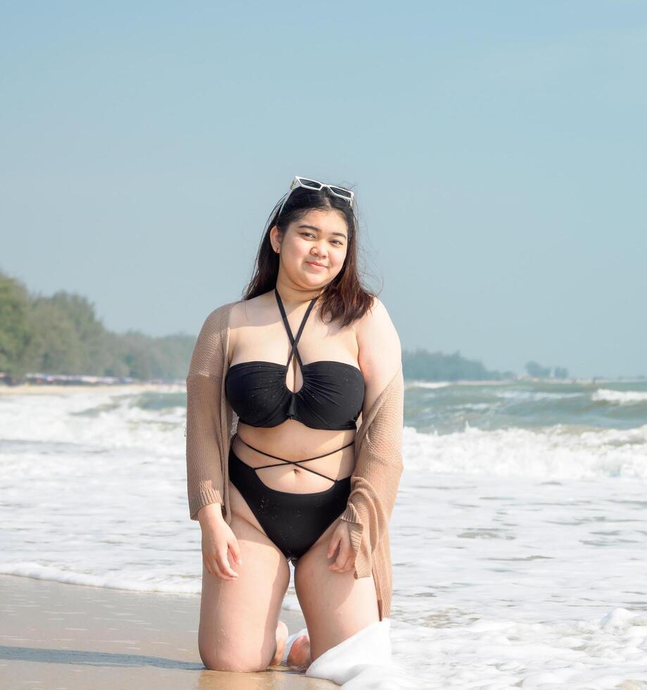 retrato jovem ásia mulher gordo gordo fofa lindo sorrir feliz Diversão apreciar relaxar bikini roupa de banho corpo sexy frente Visão mar de praia branco areia limpar \ limpo céu azul calma natureza oceano onda água viagem em feriado foto