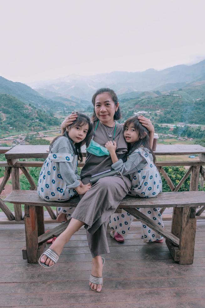 Família feliz e sorridente desfrutando sentado na varanda e olhando as montanhas e o verde foto