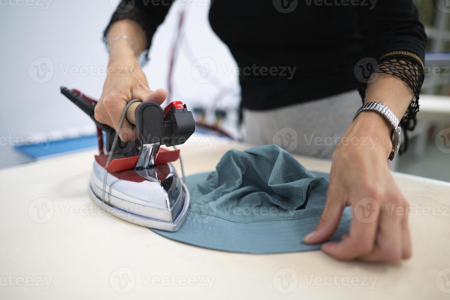 uma trabalhador ferros roupas às uma de costura fábrica foto