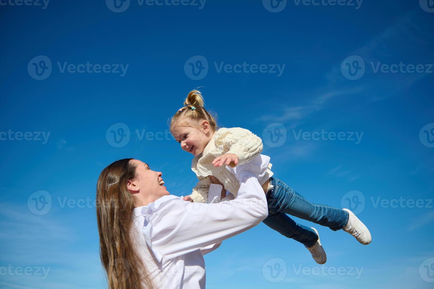 inferior Visão do uma feliz harmonioso família do uma jovem amoroso carinhoso mãe jogando acima dela pequeno bebê foto