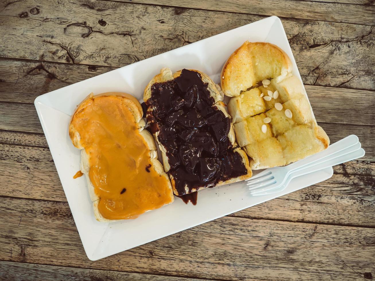 conjunto de torradas com diferentes coberturas de manteiga de amendoim, chocolate e manteiga. foto