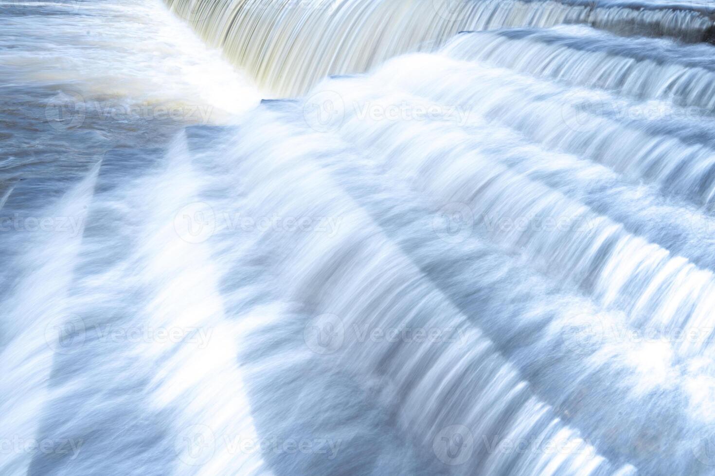 uma puro branco cascata fundo formado dentro a rio através de um Verifica barragem foto