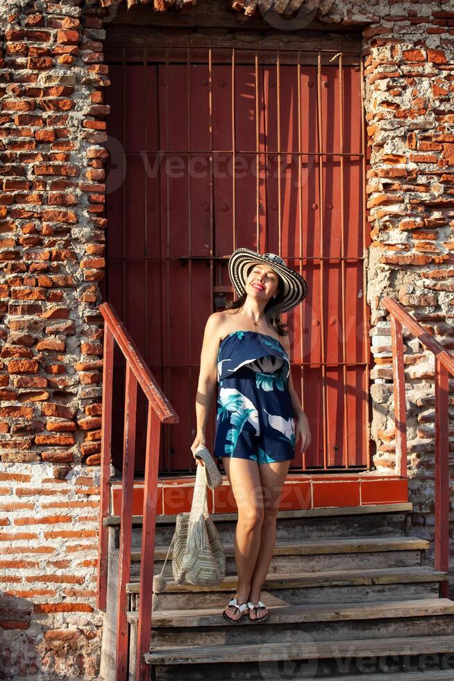 lindo mulher vestindo a tradicional colombiano chapéu chamado sombrero vueltiao às san ignácio baluarte dentro a histórico cartagena de índias murado cidade foto