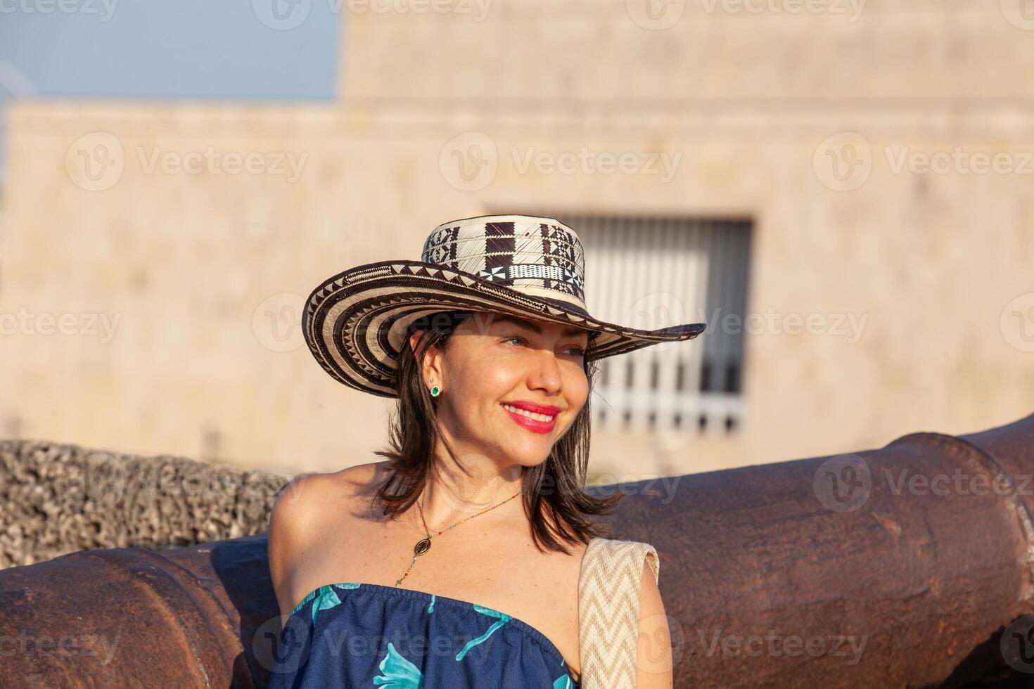 lindo mulher vestindo a tradicional colombiano chapéu chamado sombrero vueltiao às san ignácio baluarte dentro a histórico cartagena de índias murado cidade foto