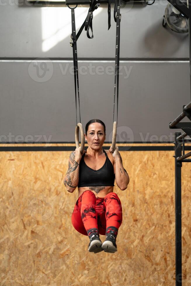 mulher Treinamento com olímpico argolas dentro uma Cruz Treinamento Centro foto