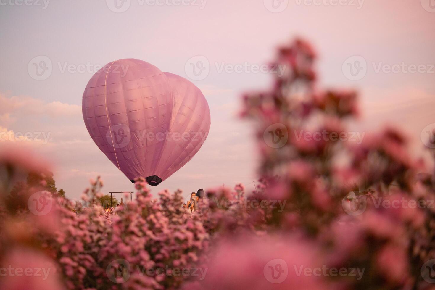 coração em forma quente ar balão flutua sobre campo do flores dentro noite, e coração em forma balões estão Além disso símbolo do amor e amizade. usando coração em forma balões Como símbolo do amor e amizade. foto