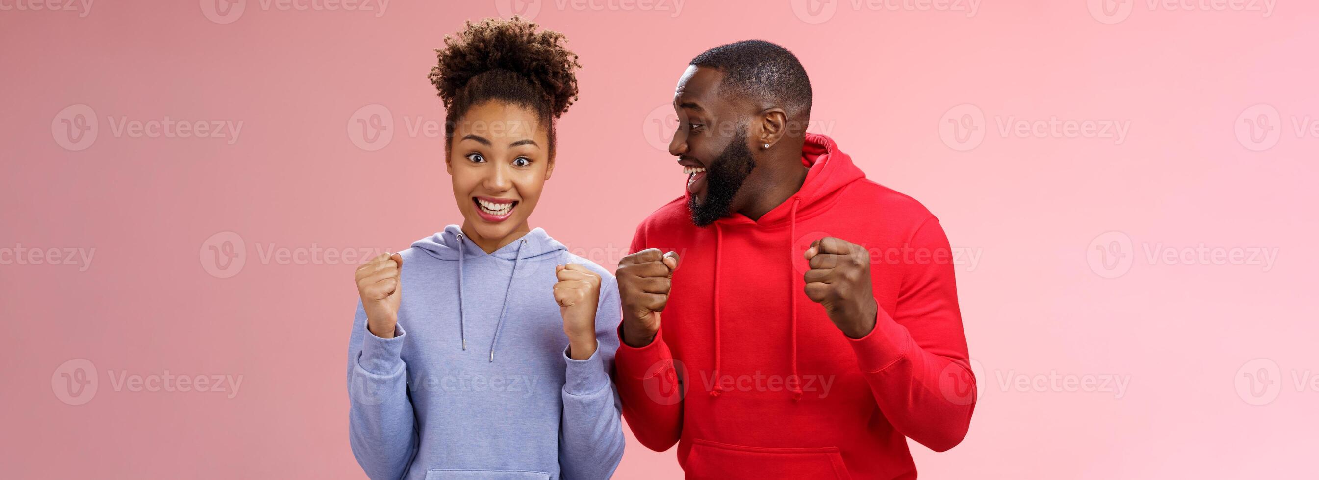 feliz entusiasmado emocionados jovem africano americano casal aperto punhos alegremente surpreso ganhando impressionante lua de mel viagem bilhetes em pé Rosa fundo triunfante sorridente amplamente a comemorar foto