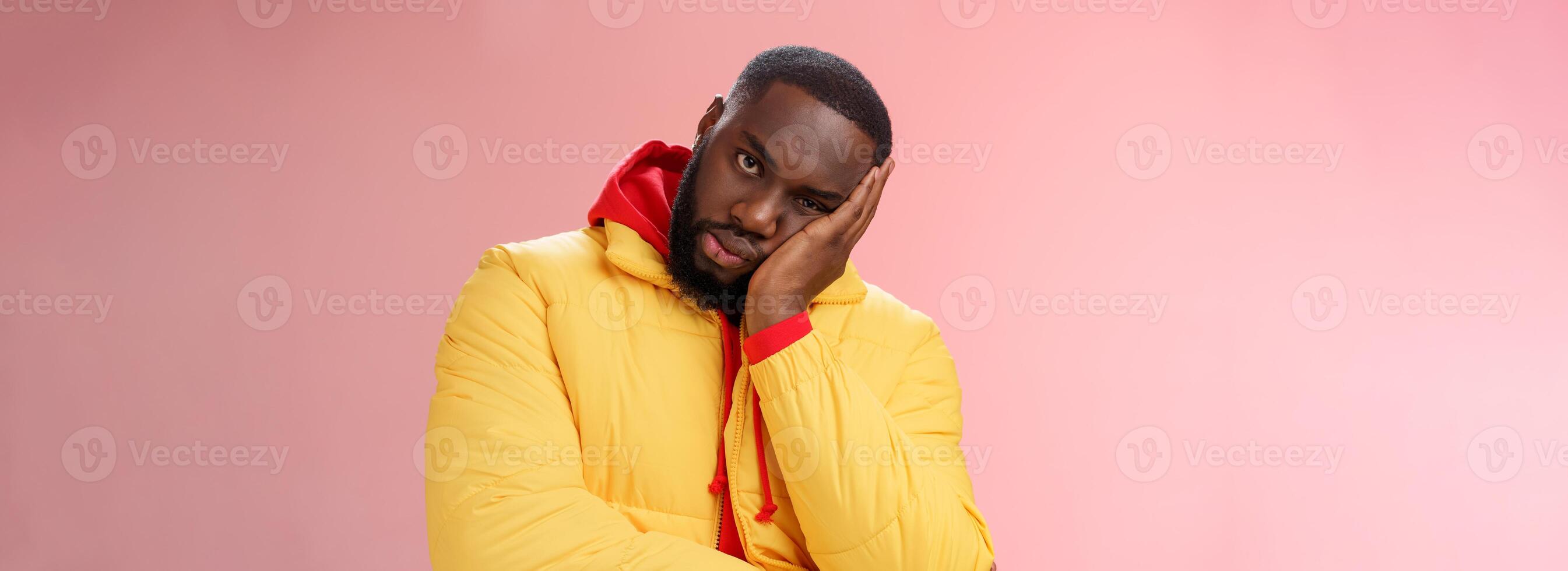 irritado incomodado chateado afro-americano barbudo homem dentro amarelo Jaqueta facepalm Veja Bravo Câmera irritado magro cabeça mão entediado alimentado acima chateado audição desinteressante mesmo histórias, Rosa fundo foto