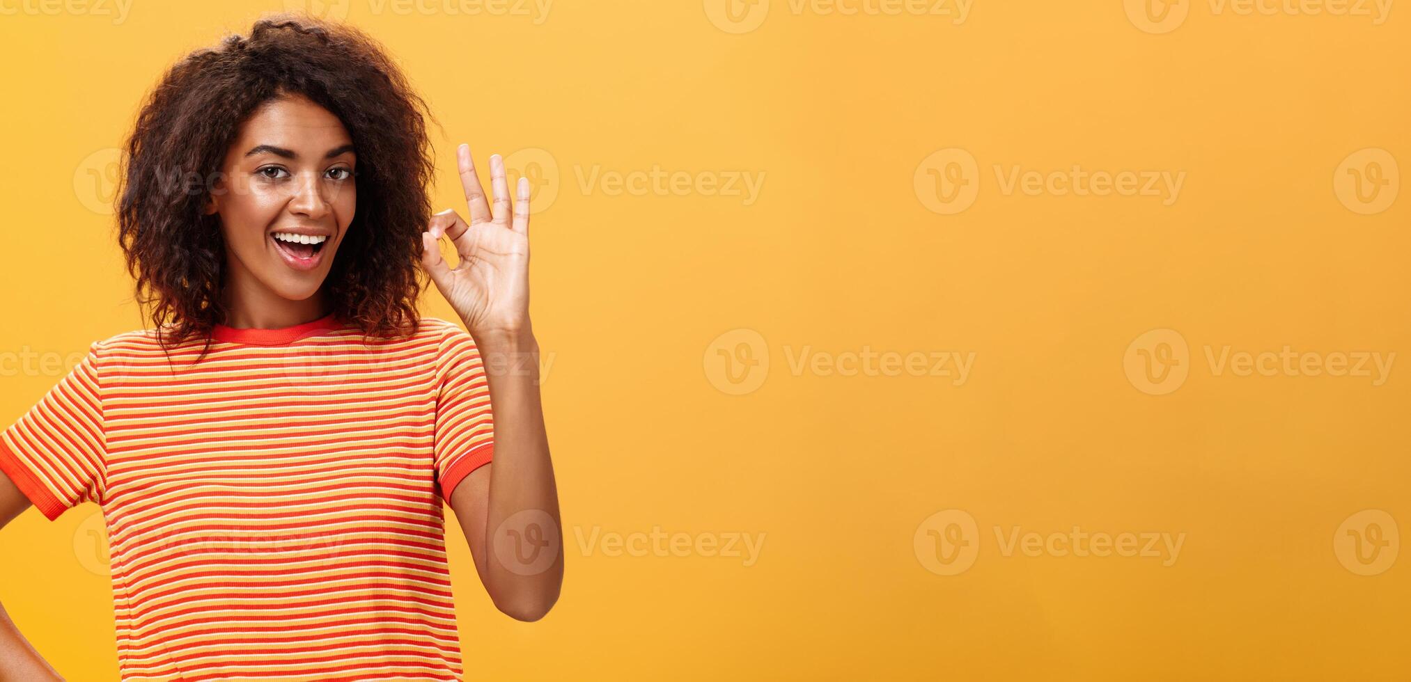 Eu obteve isto, pensar isto feito. retrato do confiante boa aparência calma e despreocupado africano americano mulher com encaracolado Penteado levantando Está bem ou excelente gesto e sorridente assegurando ela conhece o que fazendo foto