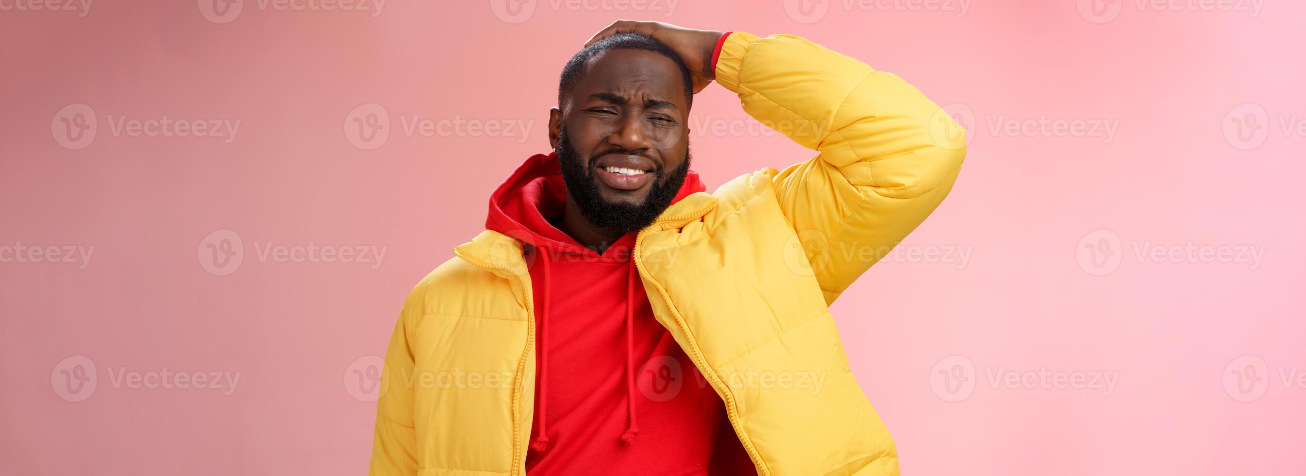 chateado sombrio afro-americano barbudo cara dentro amarelo Jaqueta vermelho moletom com capuz aguarde mãos encolhendo-se arrepender face desastre Terrível situação expressando tristeza chorando soluçando, em pé Rosa fundo foto