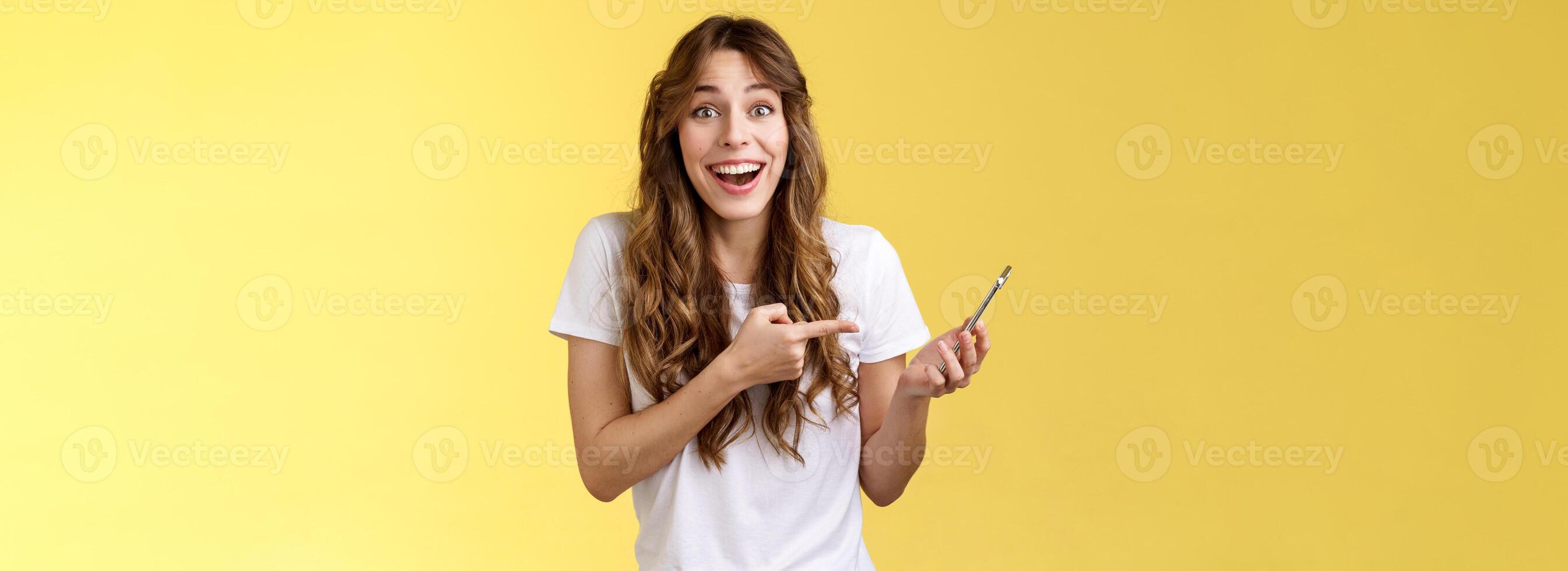 alegre feliz atraente caucasiano fêmea encaracolado Penteado sorridente rindo surpreso receber agradável Boa notícia através da telefone ligar segurando Smartphone descrever impressionante postar ler Internet apontando Móvel foto