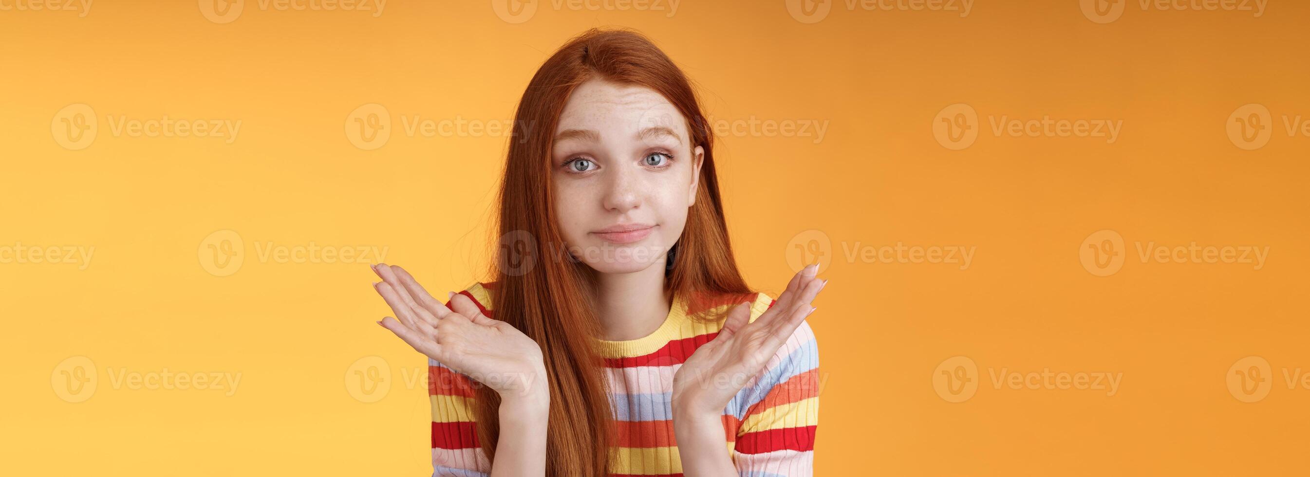 sem noção sossegado jovem ruiva boba europeu menina 20s encolhendo os ombros mãos espalhar lateralmente sorrindo Desculpe não podes responda em pé inconsciente confuso intrigado dar responder, laranja fundo foto