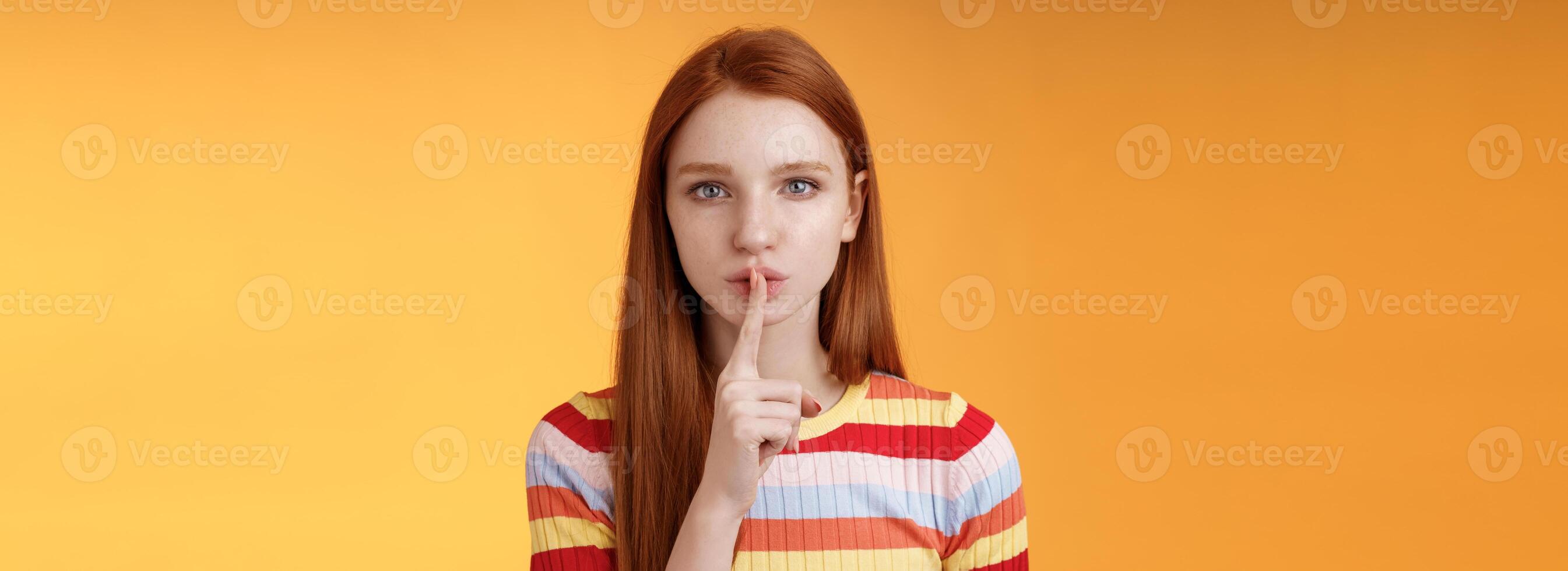 menina esconde grande quantidade segredos. sério ruiva namorada azul olhos exigem manter silencioso voz baixa mostrar shhh shush gesto índice dedo pressionado lábios, preparar surpresa, laranja fundo foto