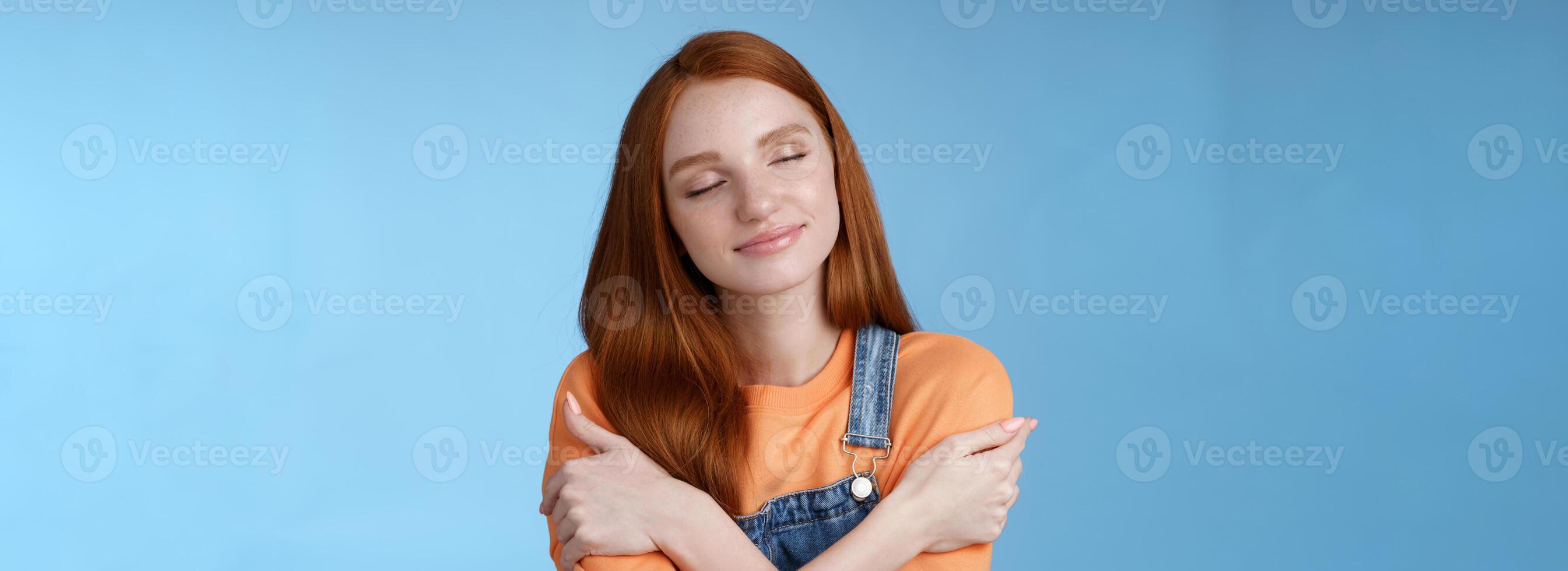 apaixonado romântico concurso gengibre menina sentir seguro conforto fechar olhos sorridente suavemente adorável sonhando acordado abraçando ela mesma relembrando namorado abraços sensual abraça, em pé azul fundo feliz foto