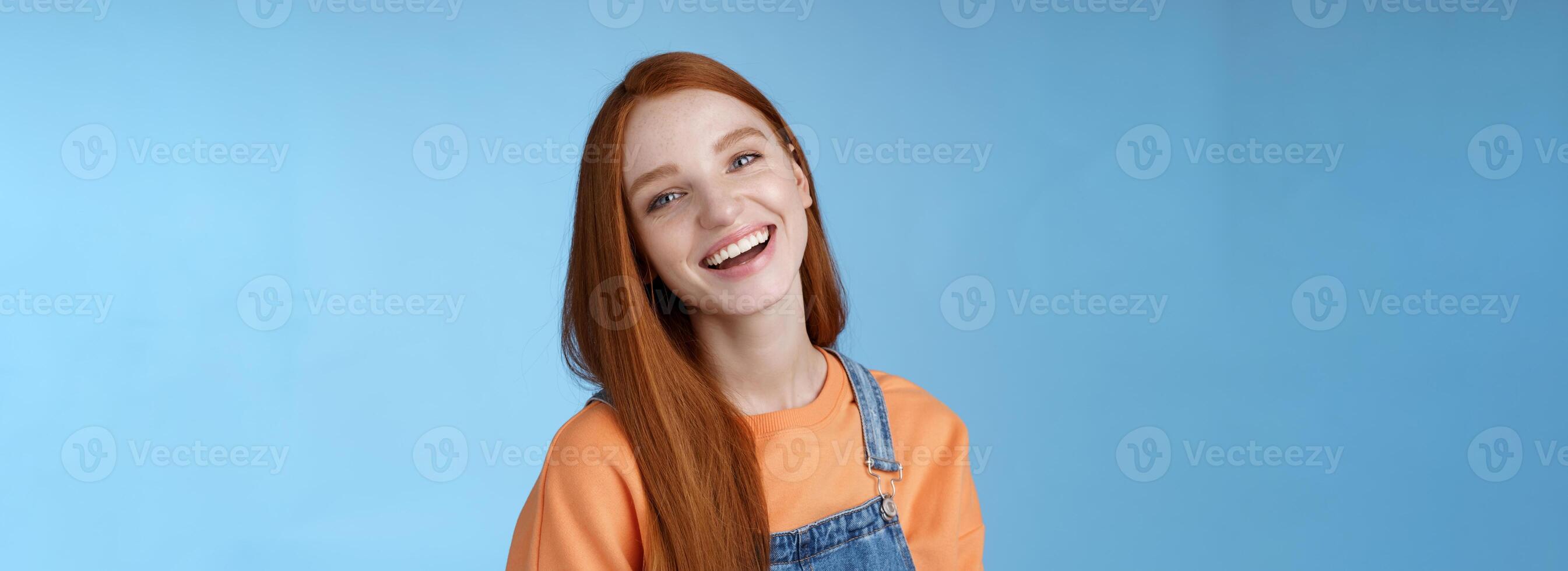 positivo extrovertido animado ruiva menina rindo alegremente tendo Diversão falando amigáveis amigos inclinação cabeça rindo brincadeira engraçado vida momentos em pé positivo por sorte azul fundo laranja camiseta foto