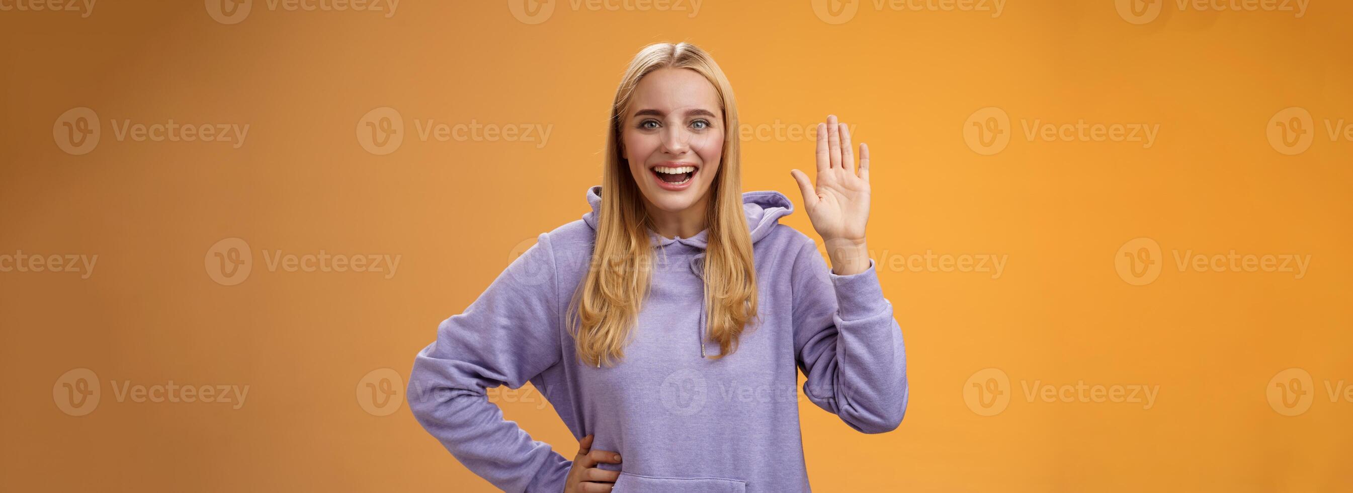 amigáveis energizado útil encantador fêmea aluna dizer Olá recém-chegados acenando elevado Palma Ei Oi gesto cumprimento acolhedor Felizmente, em pé laranja fundo sorridente amplamente foto