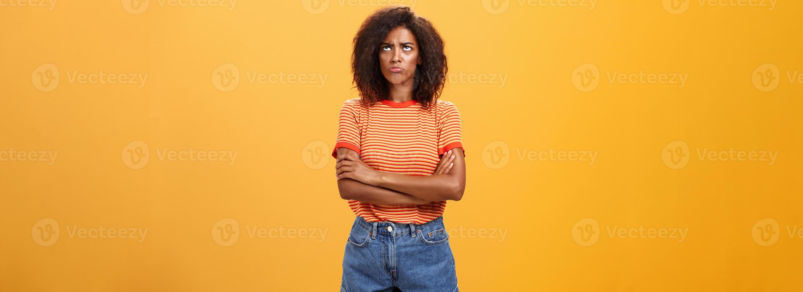 porque vida tão injusto. retrato do fofa ofendido e sombrio descontente africano americano jovem mulher com afro Penteado mau humor fazendo beicinho cruzando braços em peito olhando acima com inveja ou ciúmes foto