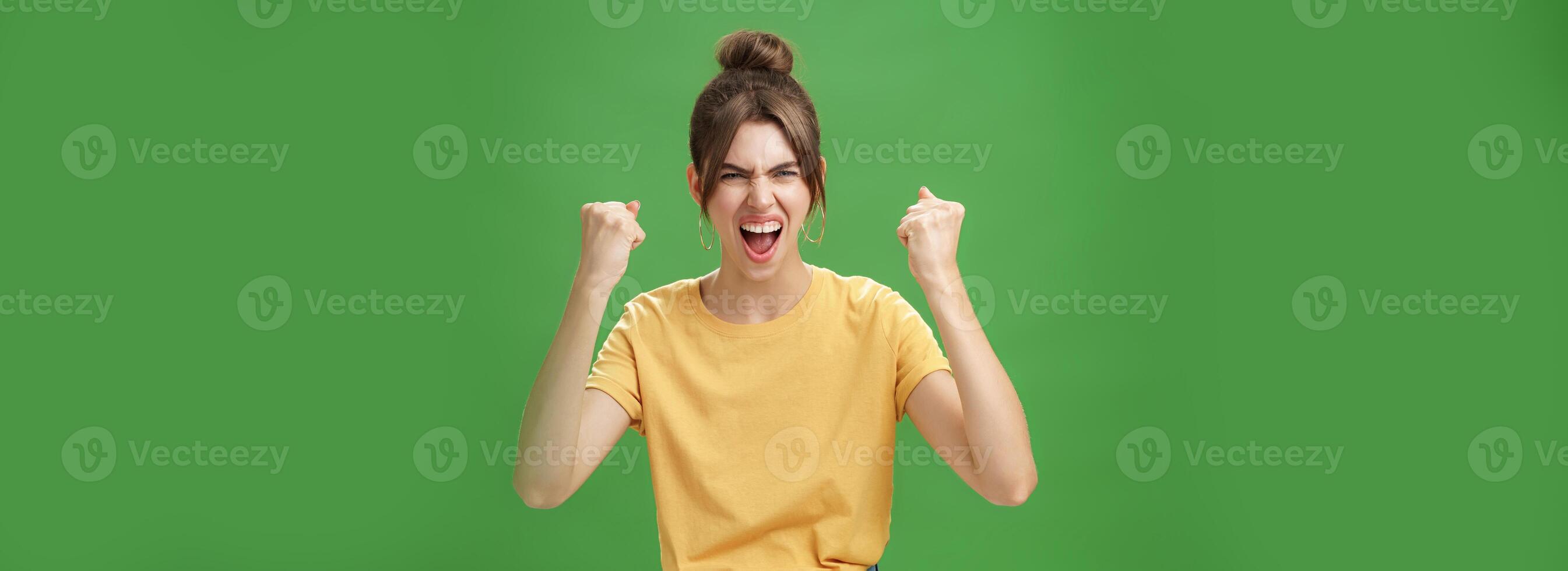 furioso e poderoso boa aparência emotivo mulher dentro amarelo camiseta com lacunado dentes gritando dentro animar ser dedicada fã, apoiando favorito equipe querendo isto ganhar levantando cerrado punhos dentro vitória foto