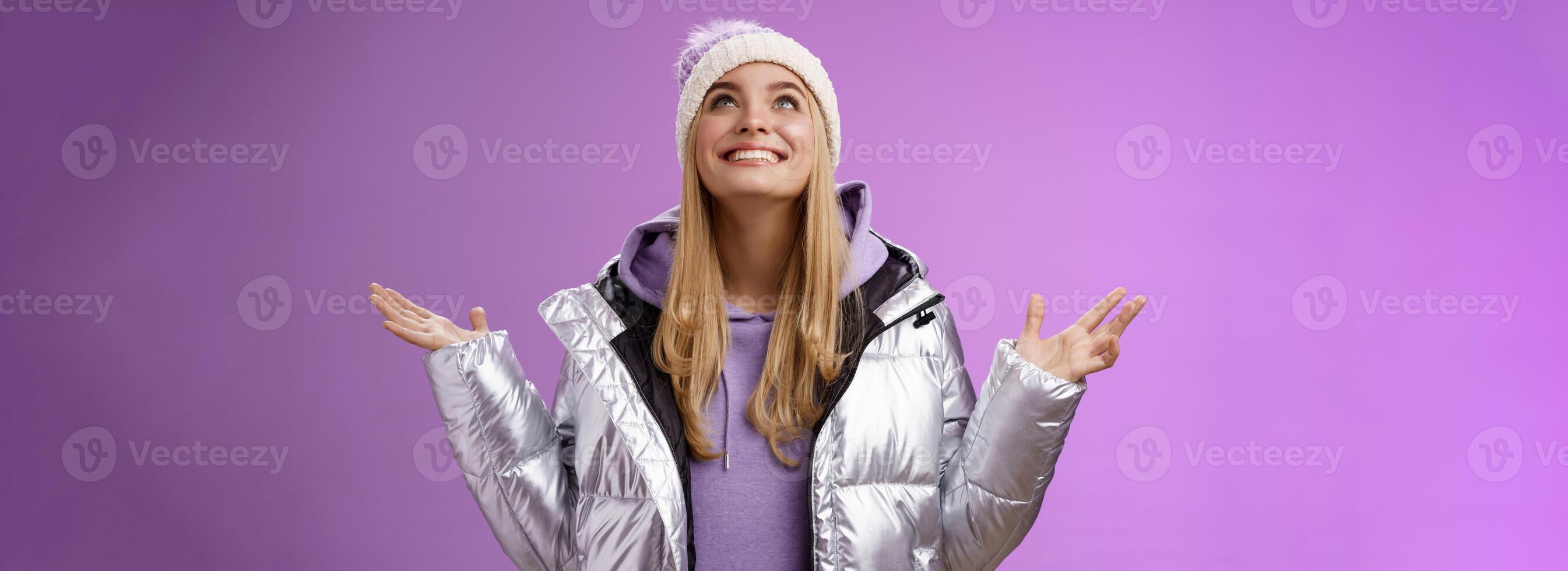 grato feliz fofa atraente loiro jovem 25s mulher dentro inverno chapéu prata na moda Jaqueta levantar mãos Veja acima grato Deus Sonhe venha verdade sorridente Deleitado realizada desejar, roxa fundo foto