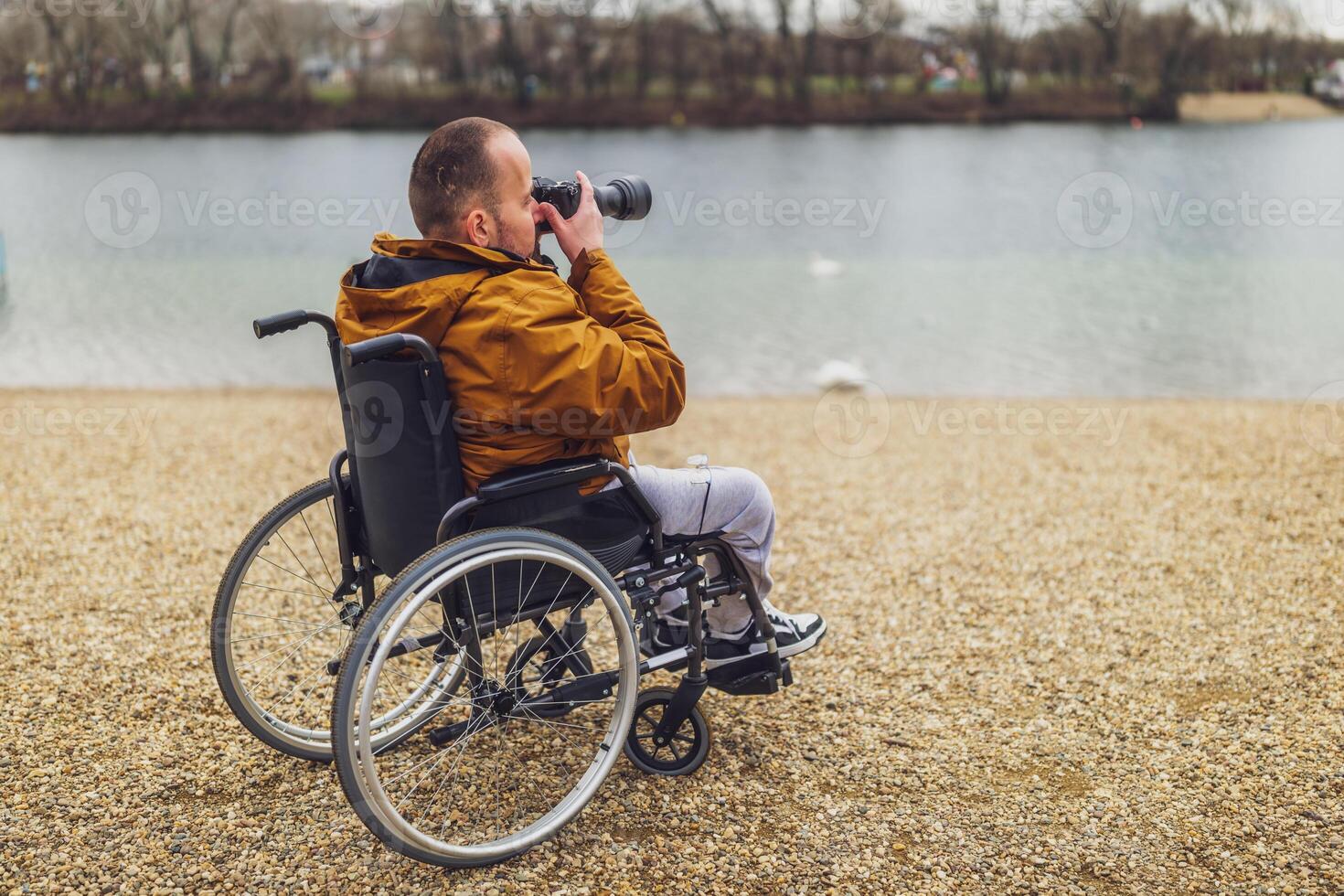 paraplégico deficiente homem dentro cadeira de rodas é fotografando ar livre. foto