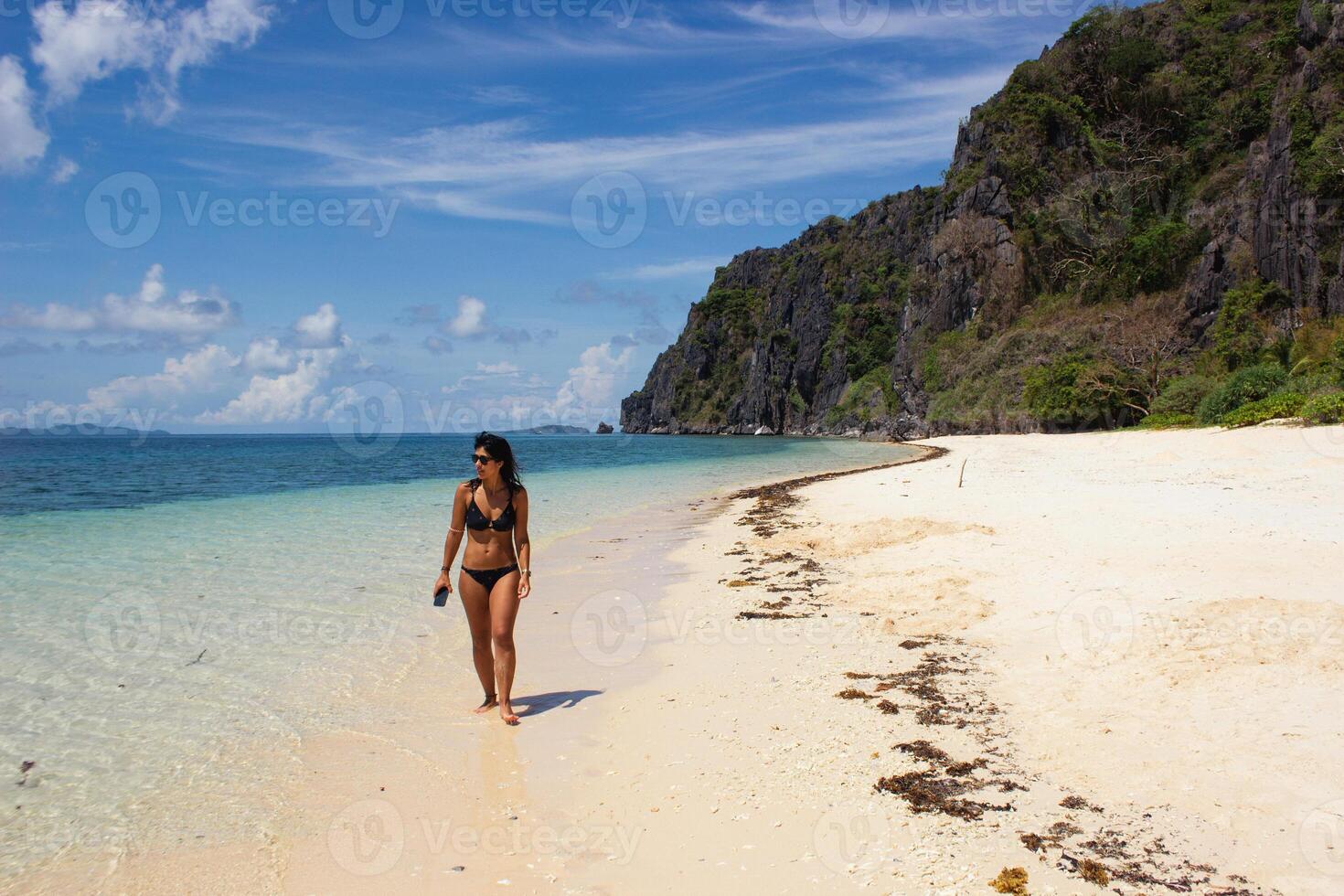 mulher caminhando em a bem areia do uma tropical de praia em uma ensolarado dia. foto