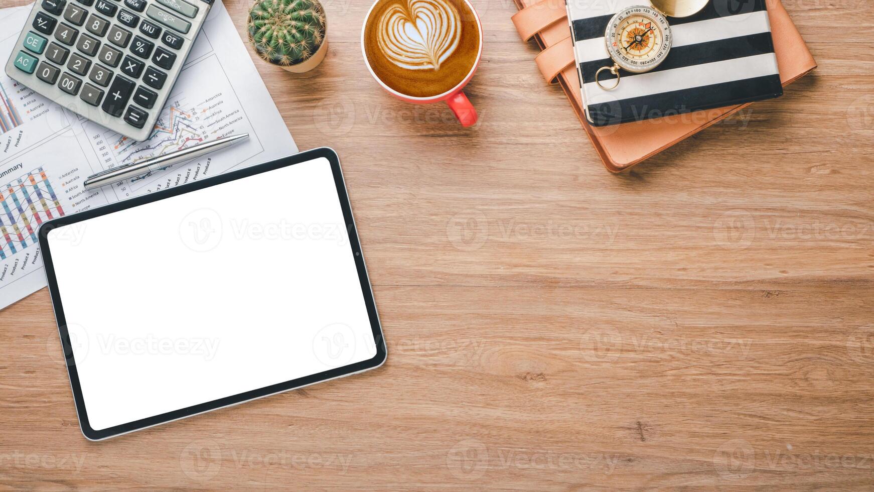 uma ordenadamente organizado área de trabalho apresentando uma tábua com uma em branco tela, financeiro gráficos, uma calculadora, e uma copo do café em uma de madeira superfície. foto