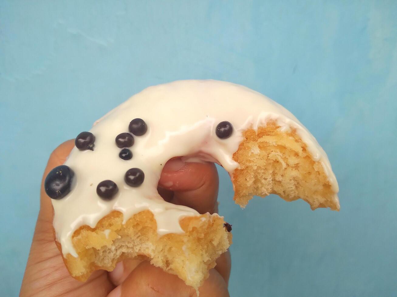 fêmea mão detém uma rosquinha em uma azul fundo. conceito confeitaria loja, pastelaria, café fazer compras. bandeira. plano deitar, topo visualizar. foto