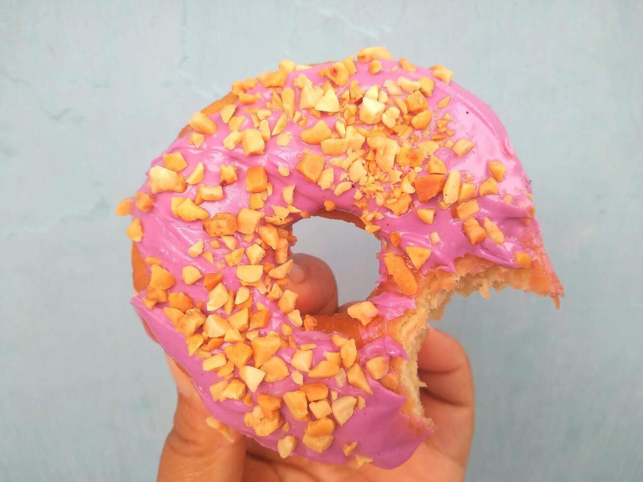 fêmea mão detém uma rosquinha em uma azul fundo. conceito confeitaria loja, pastelaria, café fazer compras. bandeira. plano deitar, topo visualizar. foto