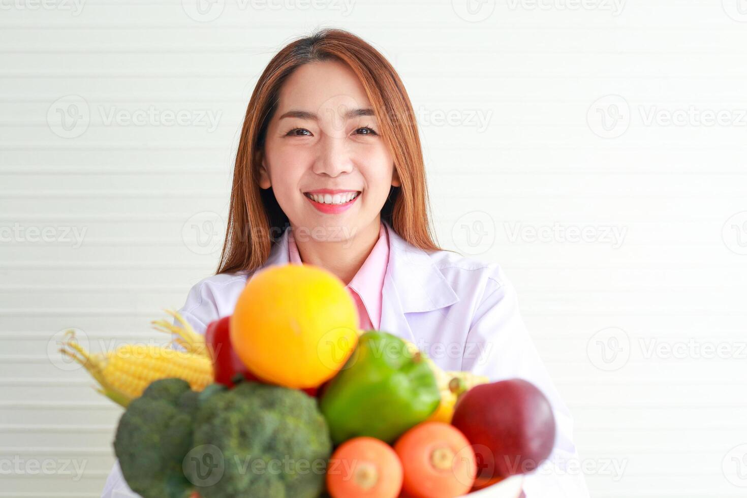 lindo ásia nutricionista segurando uma bandeja do frutas e legumes ela deram adendo e preparar nutritivo Comida comer limpar, saudável Comida. saúde Cuidado conceito foto