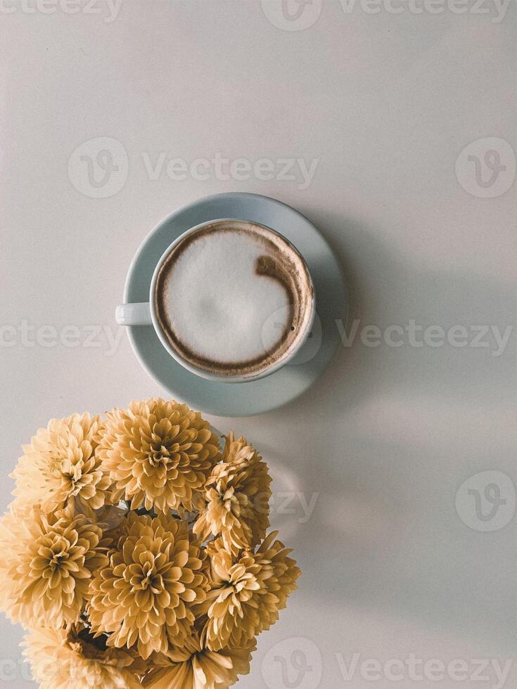 copo do café e amarelo flores em branco fundo. plano deitar, topo visualizar. foto