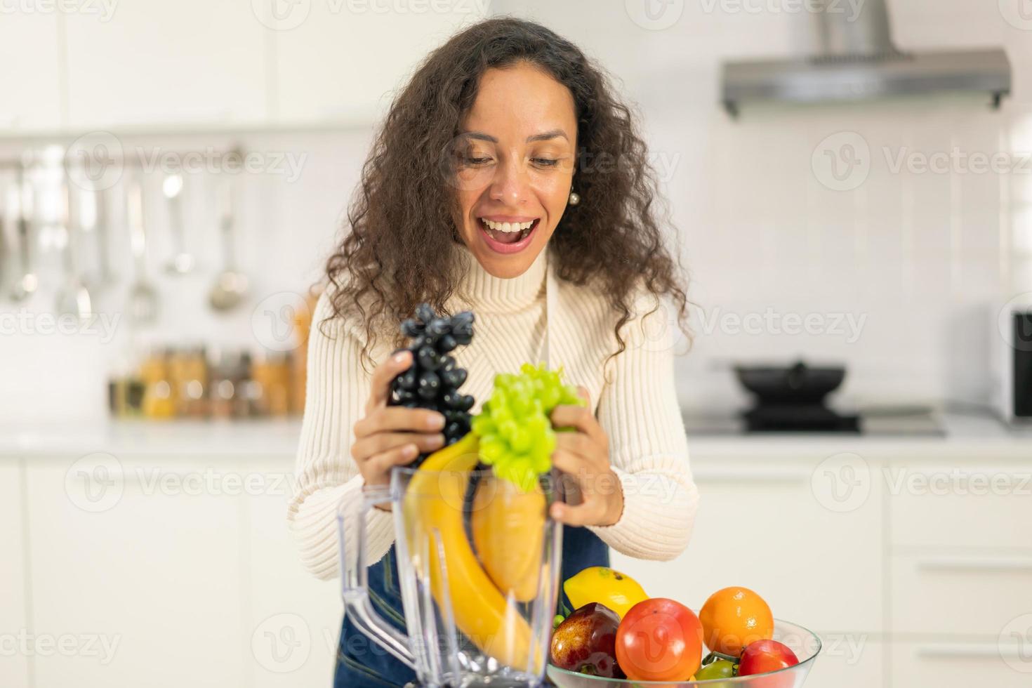 mulher latina fazendo suco na cozinha foto