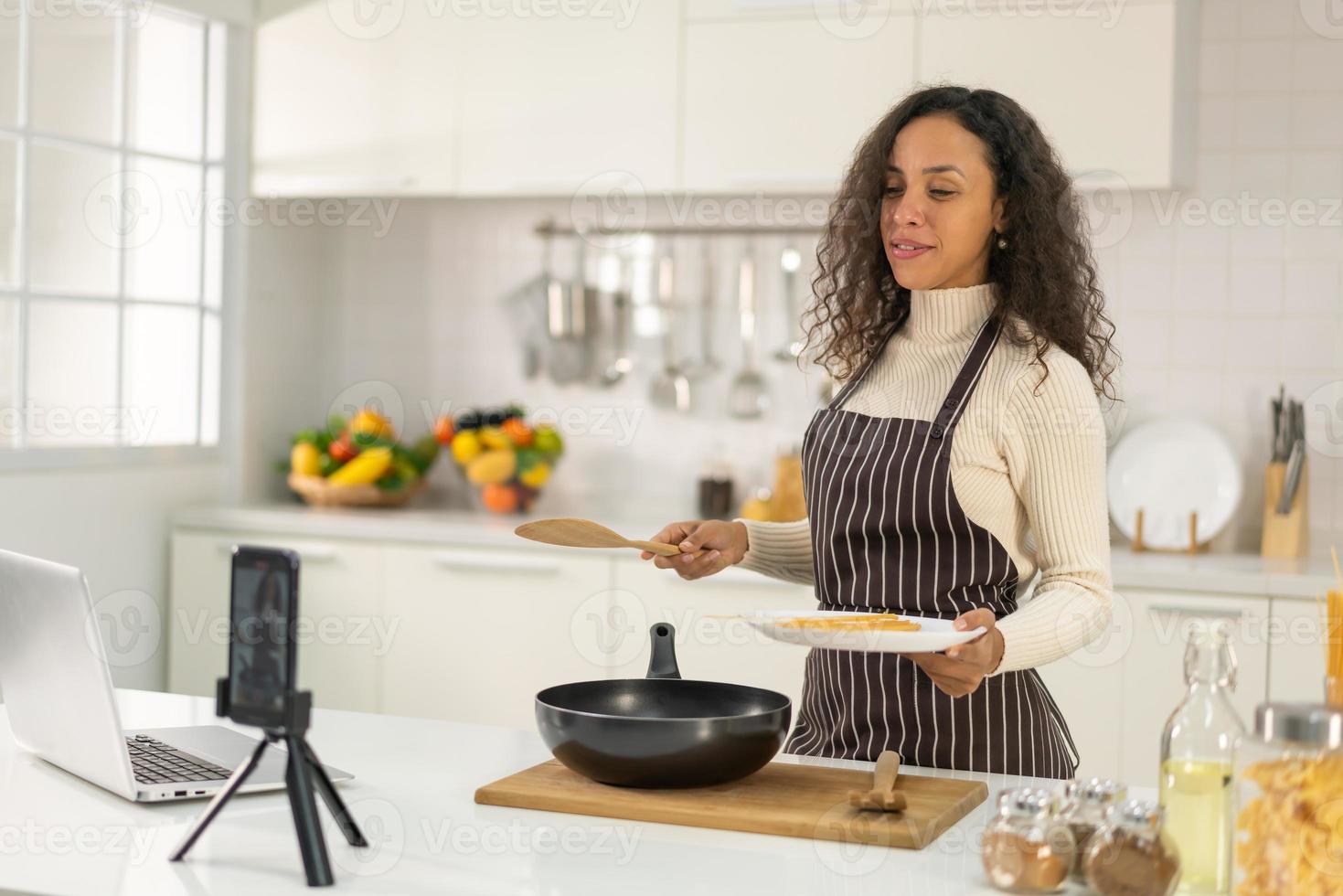 mulher latina gravando vídeo e cozinhando na cozinha foto