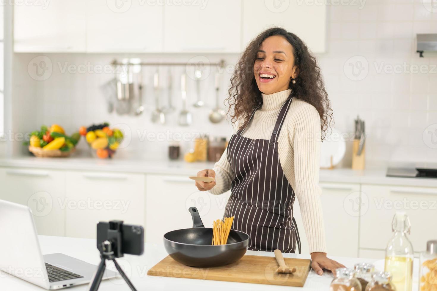 mulher latina gravando vídeo e cozinhando na cozinha foto